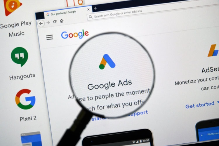 Vergrößerungsglas zeigt auf das Google Ads Logo und die Website mit Informationen zu Google Ads.