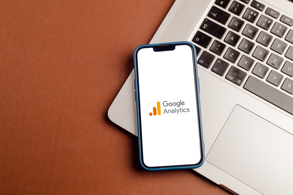 Google Analytics Logo auf Smartphone eingeblendet, welches neben einer Laptoptastatur liegt