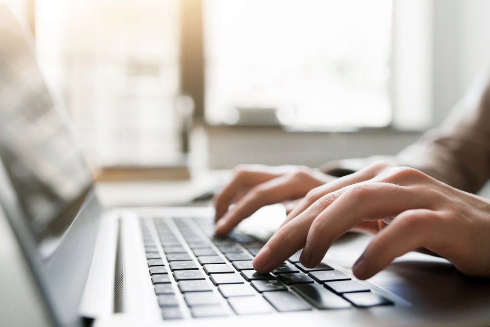 Person schreibt auf Laptoptastatur